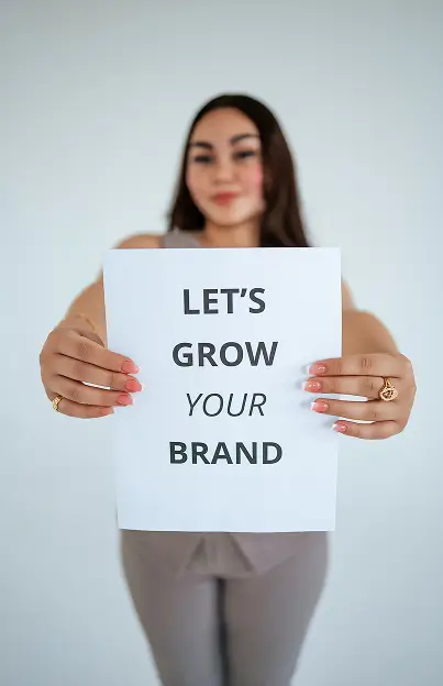 Founder holding a "Let's Grow Your Brand" Sign